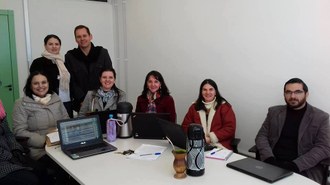 Integrantes do grupo de pesquisa sentados ao redor de uma mesa