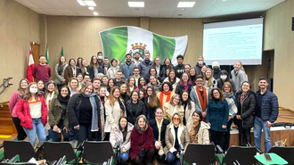 Foto em plano aberto, com muitas pessoas em um auditório