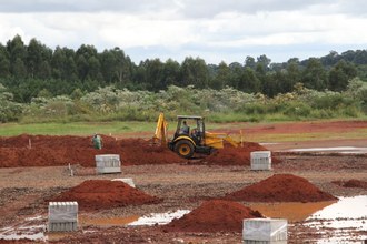 Foto em plano aberto, com máquina mexendo na terra