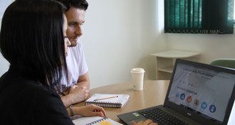 dois estudantes olhado para a tela do notebook