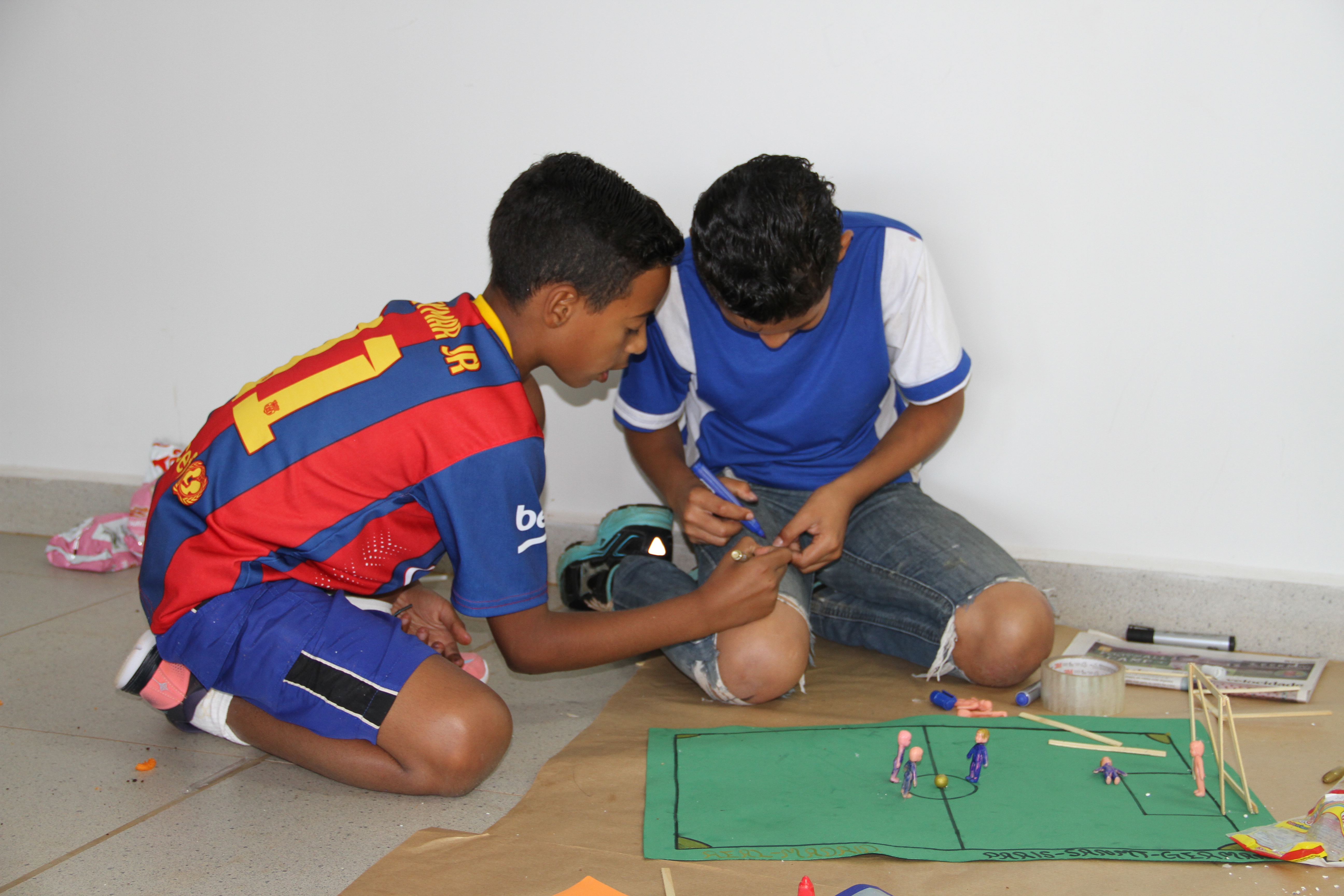 Duas crianças montando uma maquete de um campo de futebol