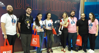 Pessoas em pé, em frente à placa do evento SW