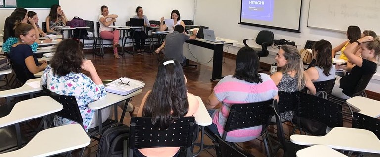 Fotografia mostra sala de aula com pessoas em reunião, sentadas em círculo