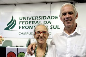 Em plano médio estão os dois pesquisadores olhando para a câmera e com o fundo do banner da UFFS - Campus Chapecó