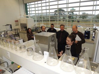 Foto de uma pessoa explicando o funcionamento de uma máquina para outras pessoas
