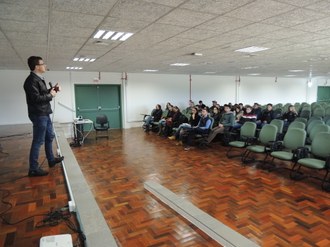 Um homem em pé palestrando para a plateia que está sentada