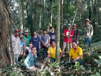 Na imagem, um grupo de pessoas posa para uma foto no interior da Mata Atlântica.