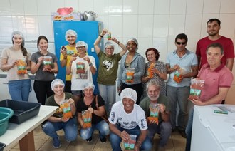 Fotografia mostra um grupo de pessoas posando para foto. As pessoas seguram das mãos amostras dos produtos desenvolvidos.