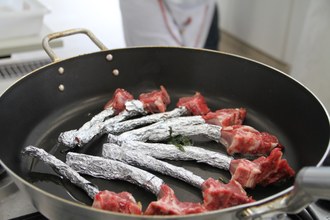 Na imagem carne é preparada em frigideira.