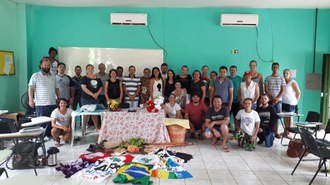 Estudantes e professores posam para foto em sala de aula. Em frente ao grupo estão posicionadas bandeiras de movimentos sociais e a Bandeira do Brasil.