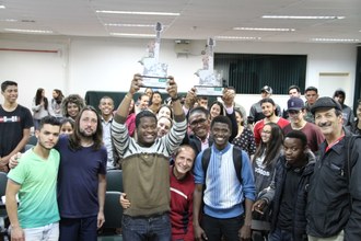 Na imagem grupo de pessoas posa para foto. Os vencedores seguram os troféus recebidos.