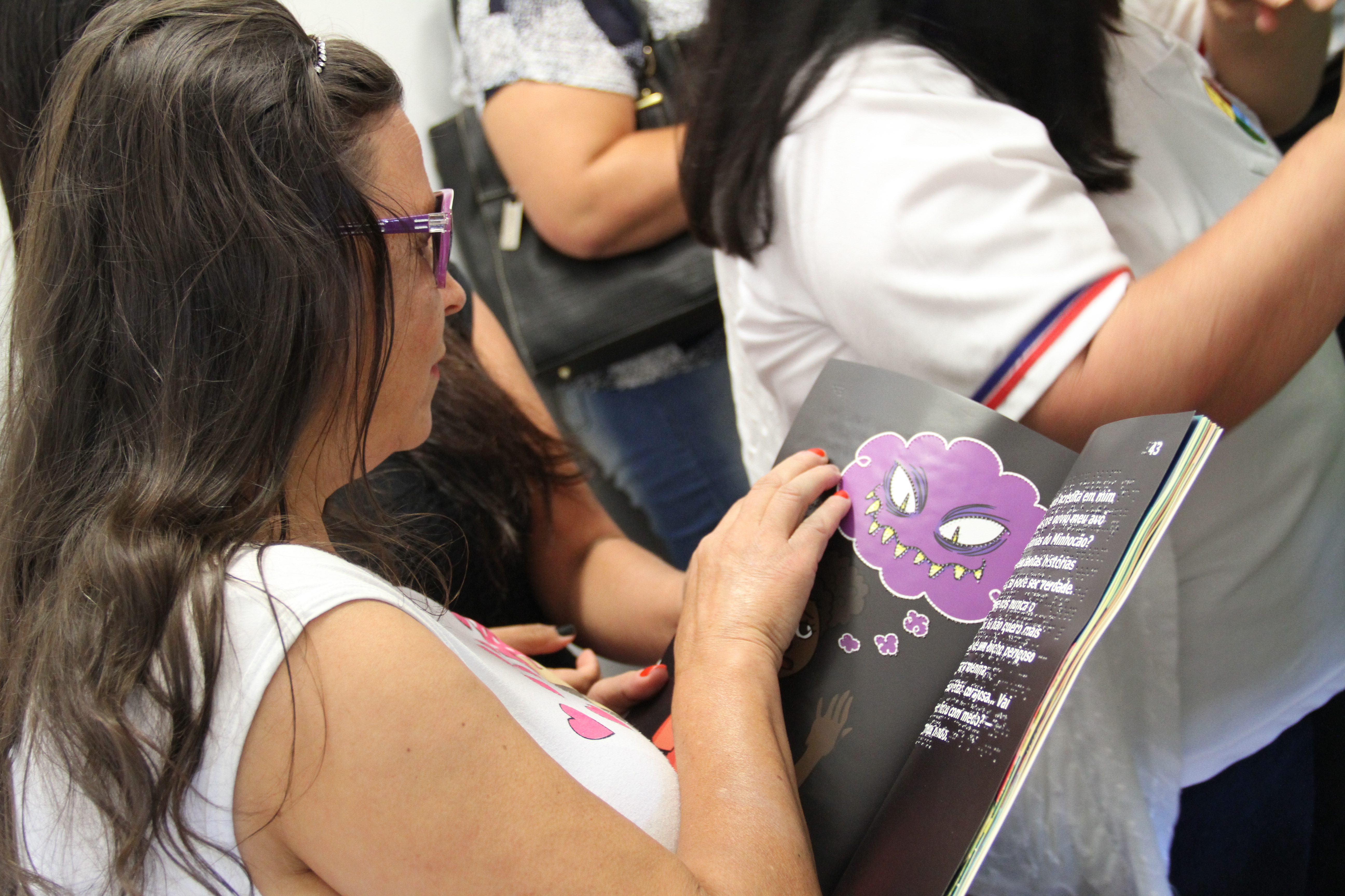 Aluna lê figura em livro no sistema braille.