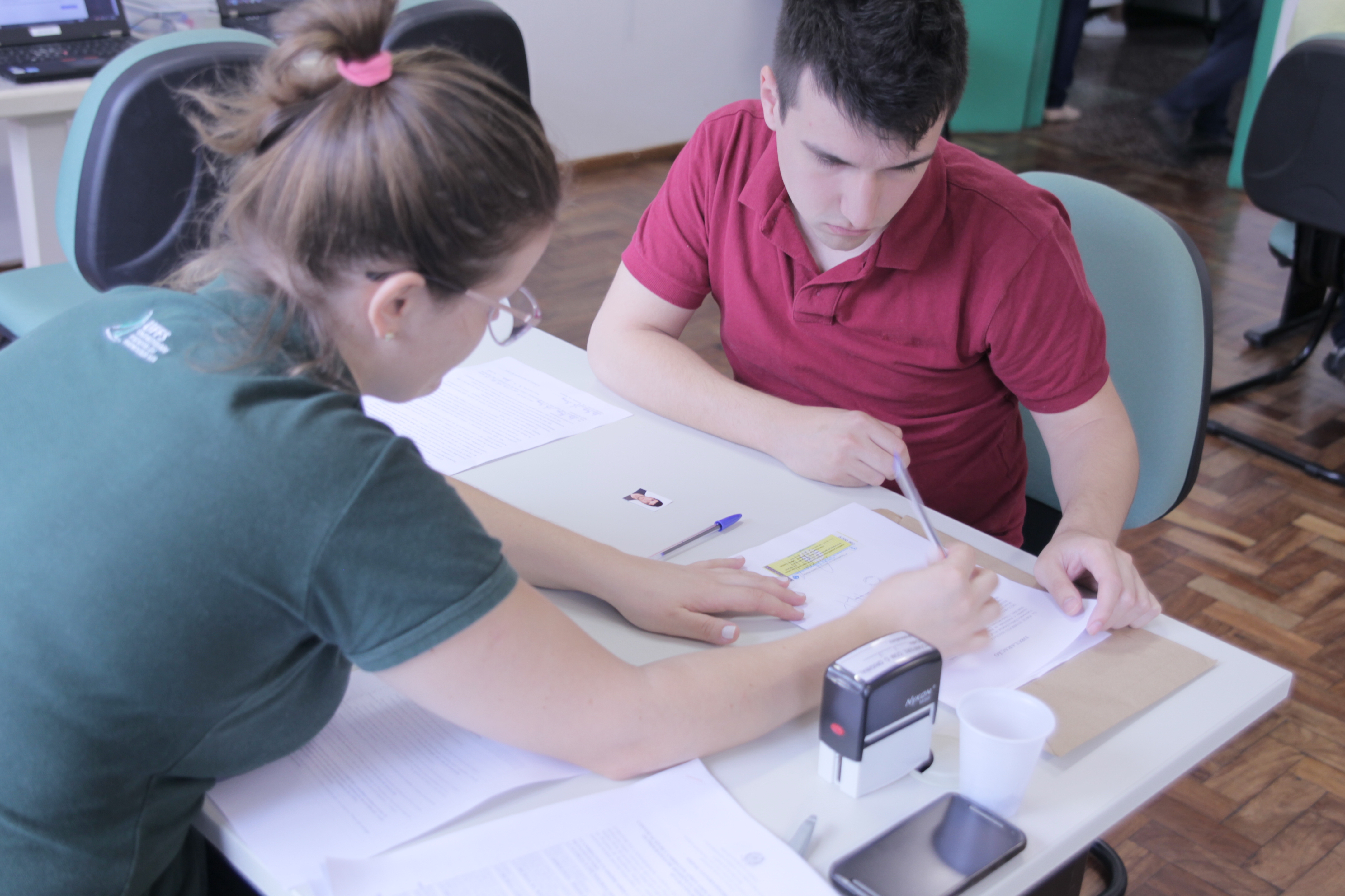 Foto em plano fechado mostrando um atendente da UFFs e um candidato conferindo documentos