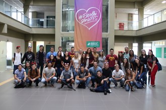 Foto em plano aberto dos novos alunos e calouros lado a lado posando para a foto no hall de entrada do bloco A