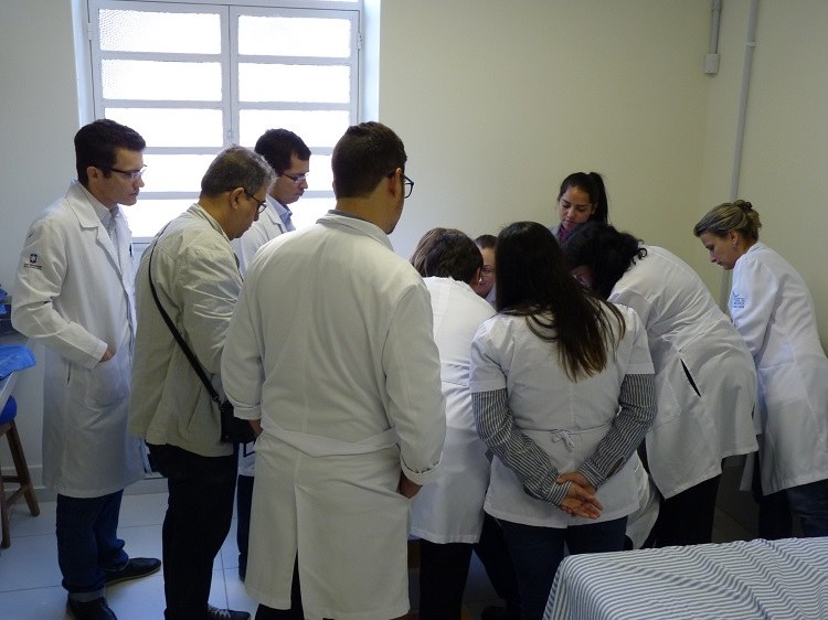 Foto da equipe de treinandos acompanhando aplicação de gesso em paciente