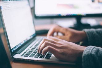 Mãos sobre um teclado de computador.