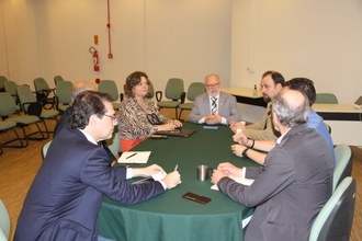 seis homens e uma mulher sentados ao redor de uma mesa